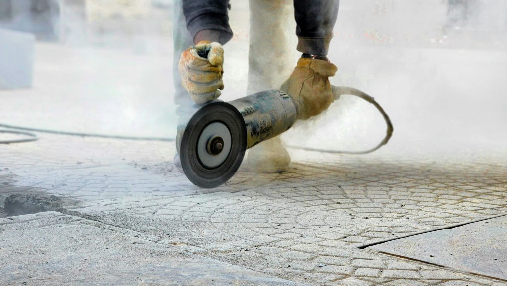 A professional technician using a floor grinder to level uneven marble tiles